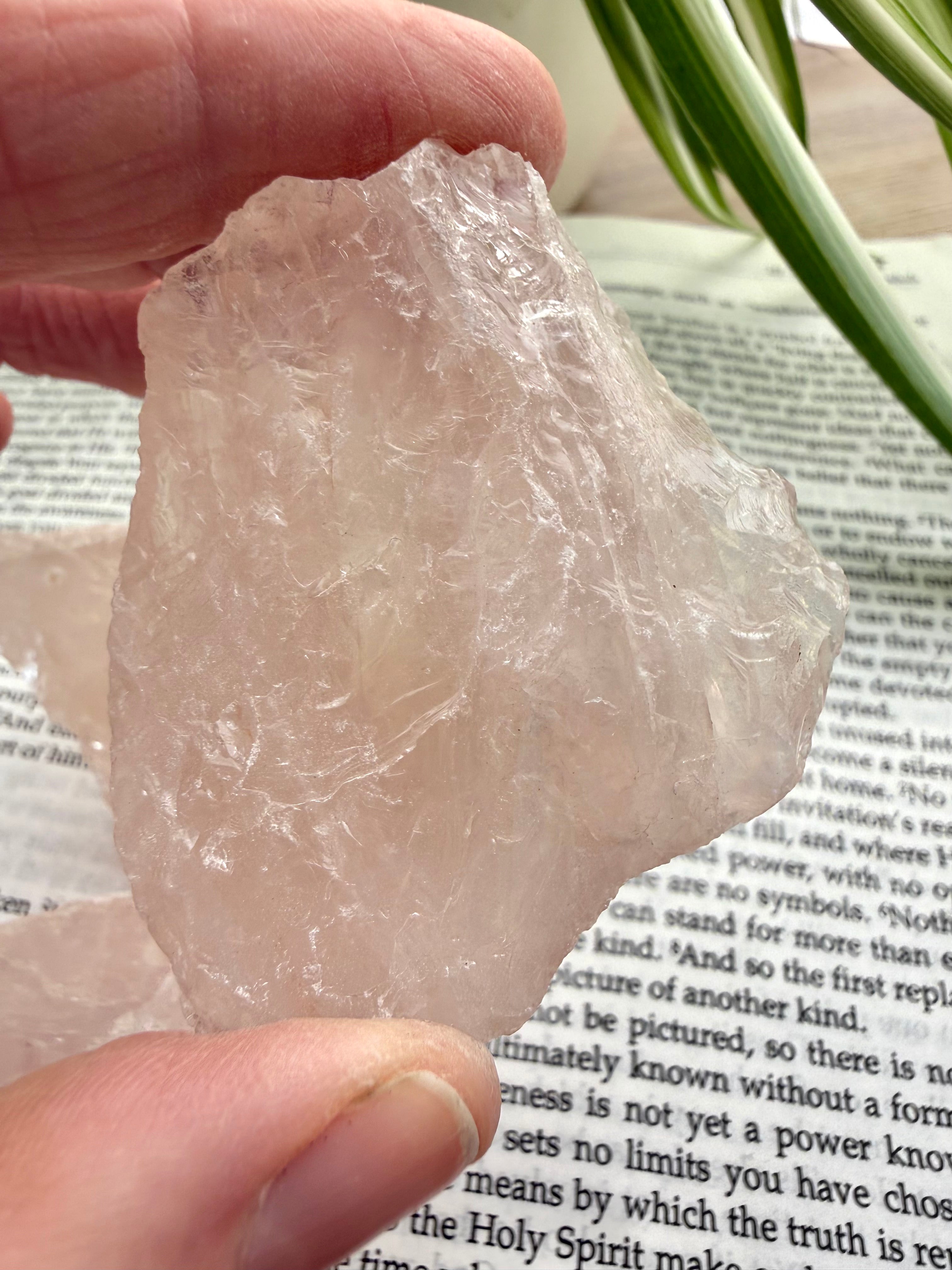 Small rose quartz held in between fingers over a book