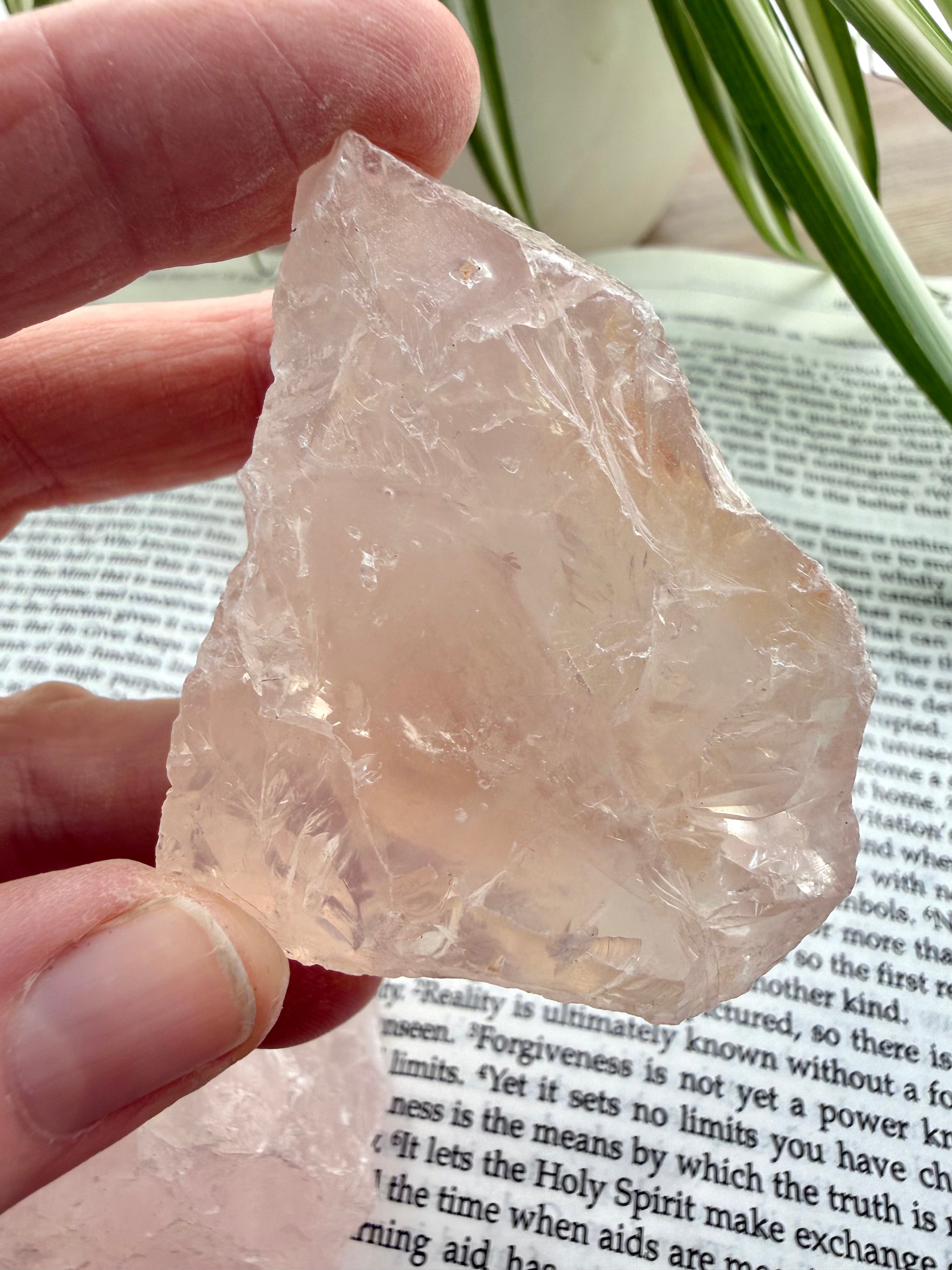 Rose quarrtz held between 2 fingers over a book 
