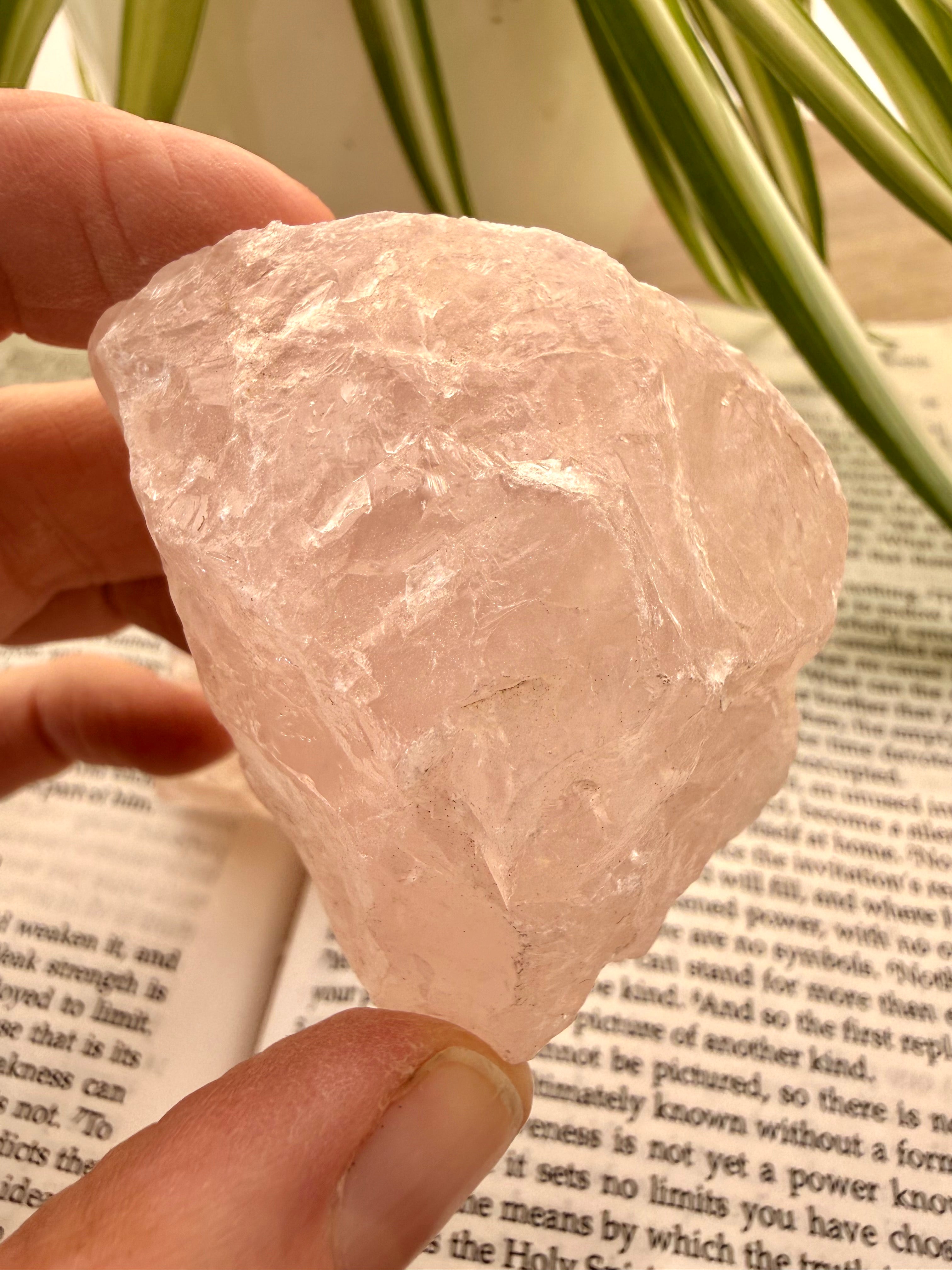 rose quartz held between fingers over a book 