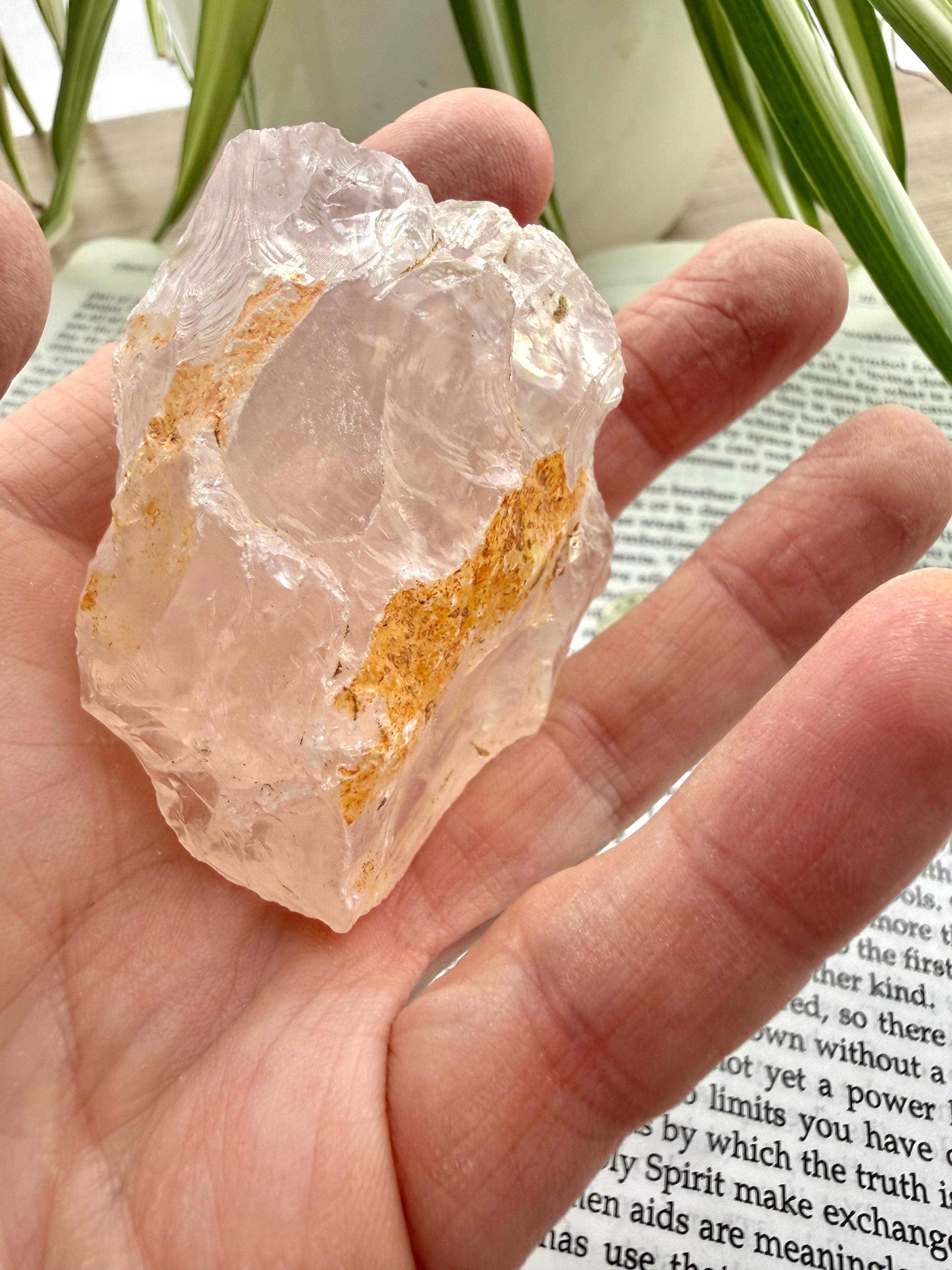 Hand holding a large crystal with gold inclusions, blurred background