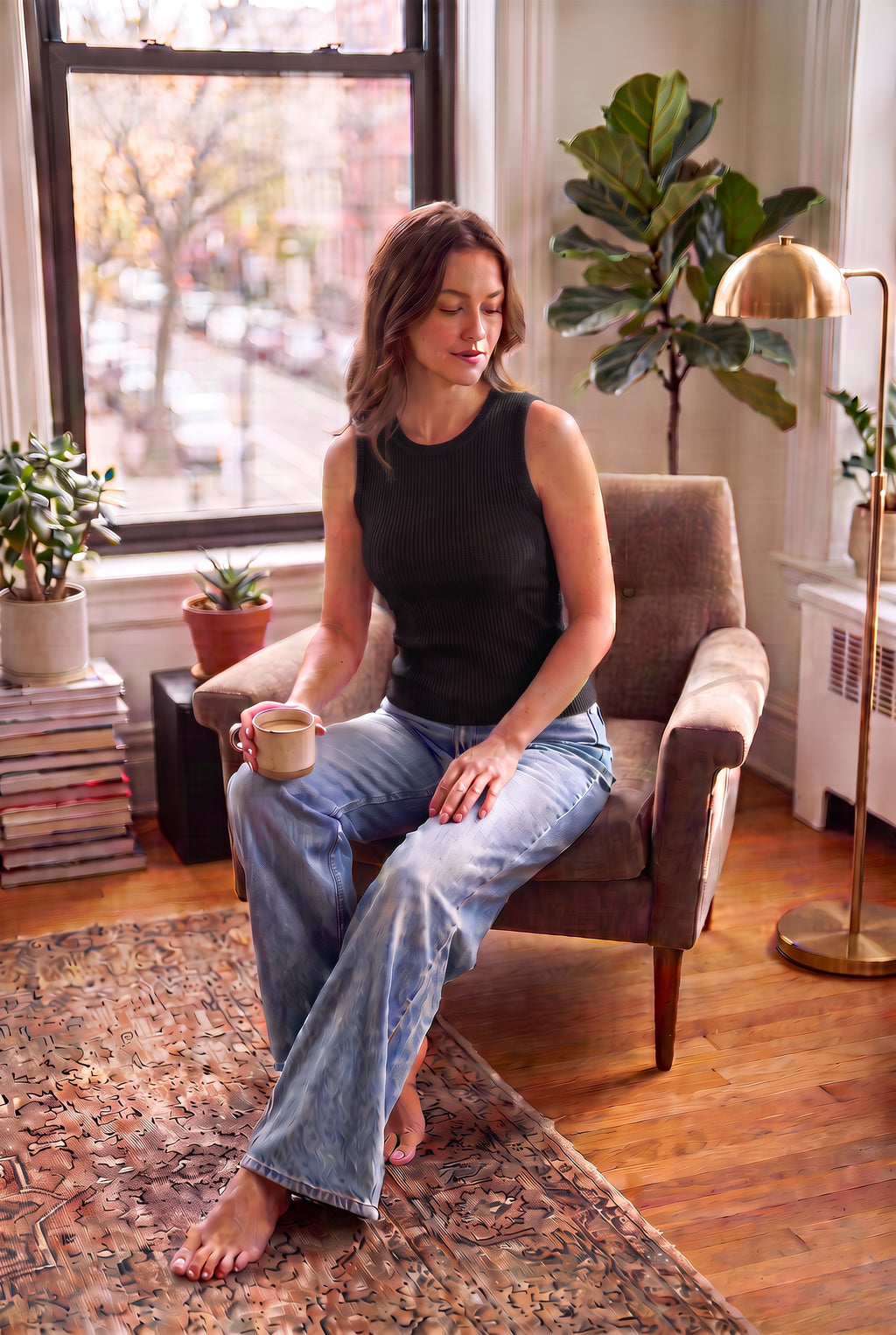 A hip-length bamboo crew neck tank featuring subtle textured detailing on a woman sitting in living room wearing jeans  - black coloured top 