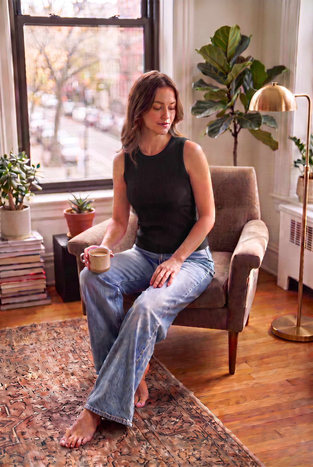 A hip-length bamboo crew neck tank featuring subtle textured detailing on a woman sitting in living room wearing jeans  - black coloured top 