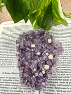 Amethyst cluster with calcite points lying flat on a book 