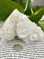 Clear apophyllite crystal rock on a book with leaves in the background