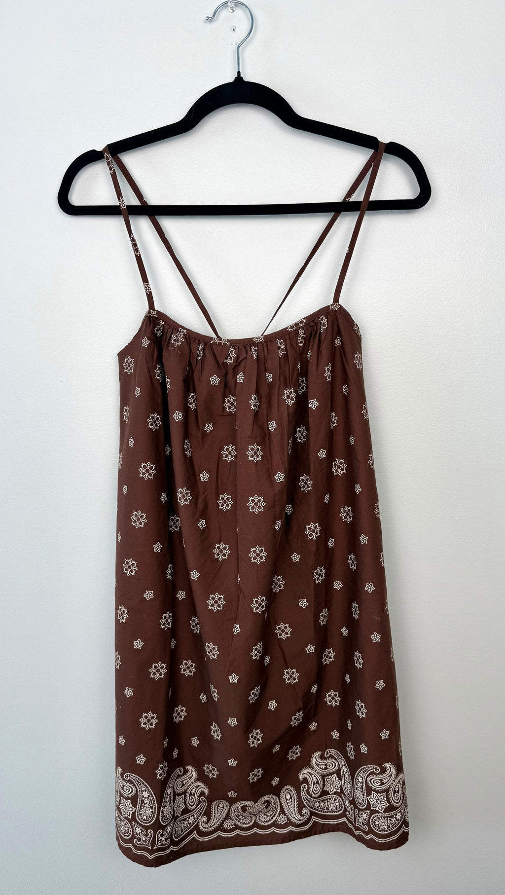 Aritzia brand brown floral dress on a hanger against a white background