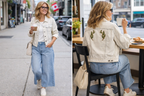 Aritzia Talula Distressed Denim Jacket at Blue Sparrow Shop on woman drinking coffee