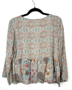 Back view of Mahla mixed print blouse in soft sage and coral geometric pattern with flowy peplum hem and relaxed silhouette in breathable modal fabric.