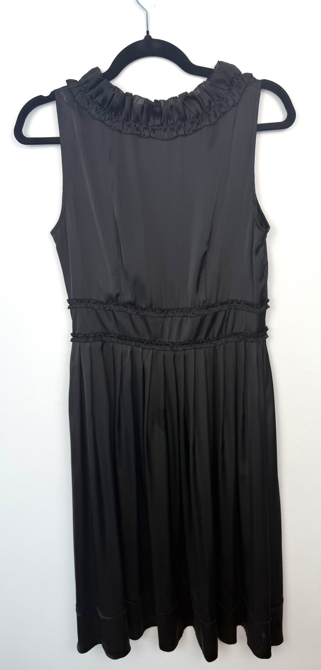 Back view of black Sandra Angelozzi sleeveless dress with ruffle trim neckline and gathered waist.