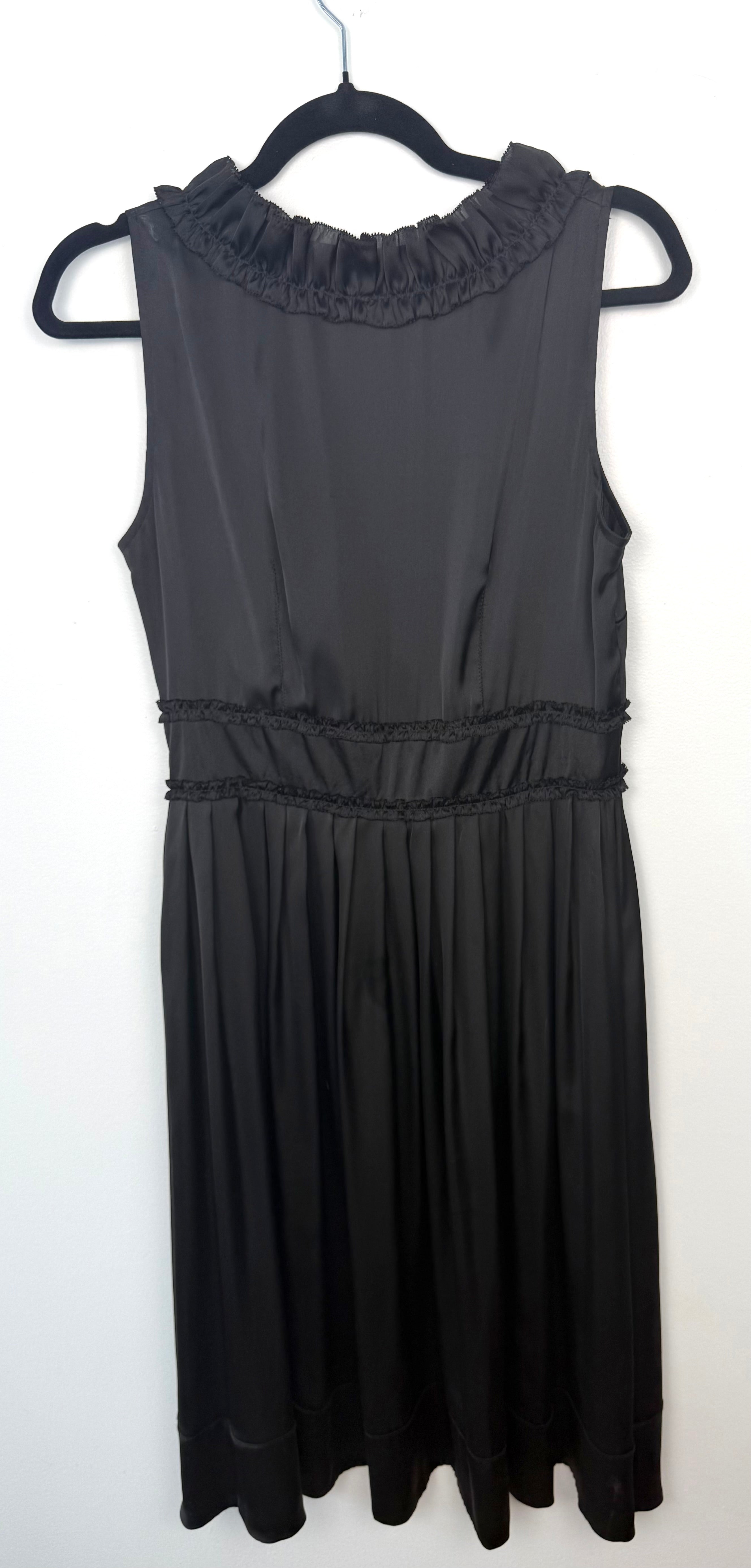Back view of black Sandra Angelozzi sleeveless dress with ruffle trim neckline and gathered waist.