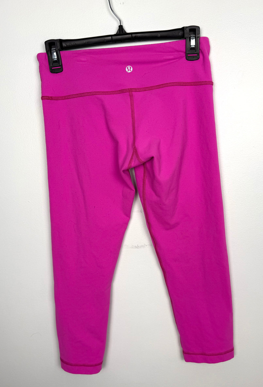 Back view of lululemon hot pink capris showing logo and waistband