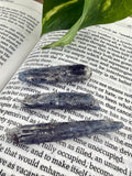 Three pieces of dark blue stone on an open book with green leaves.
