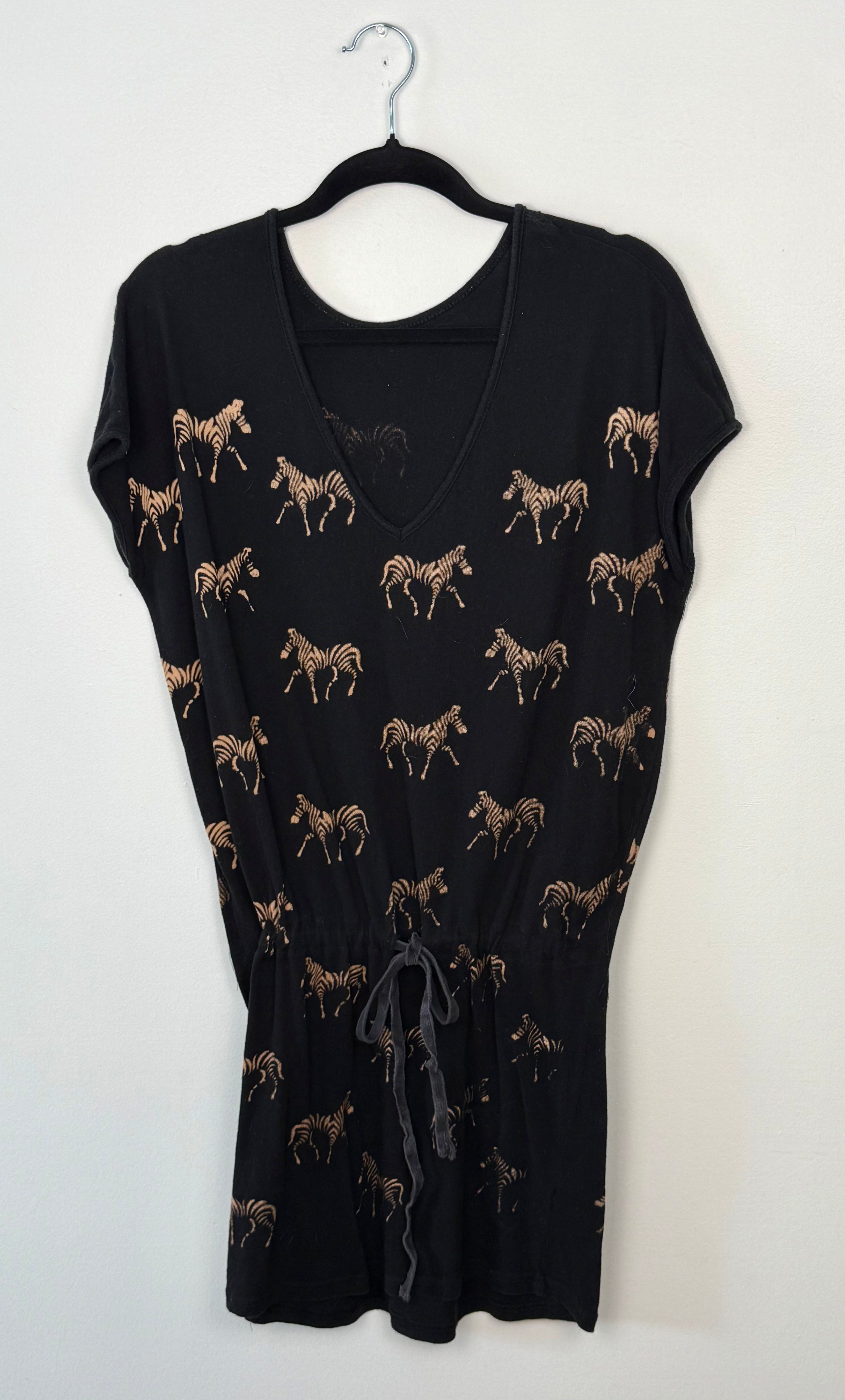Black dress with zebra pattern on a hanger against a white background
