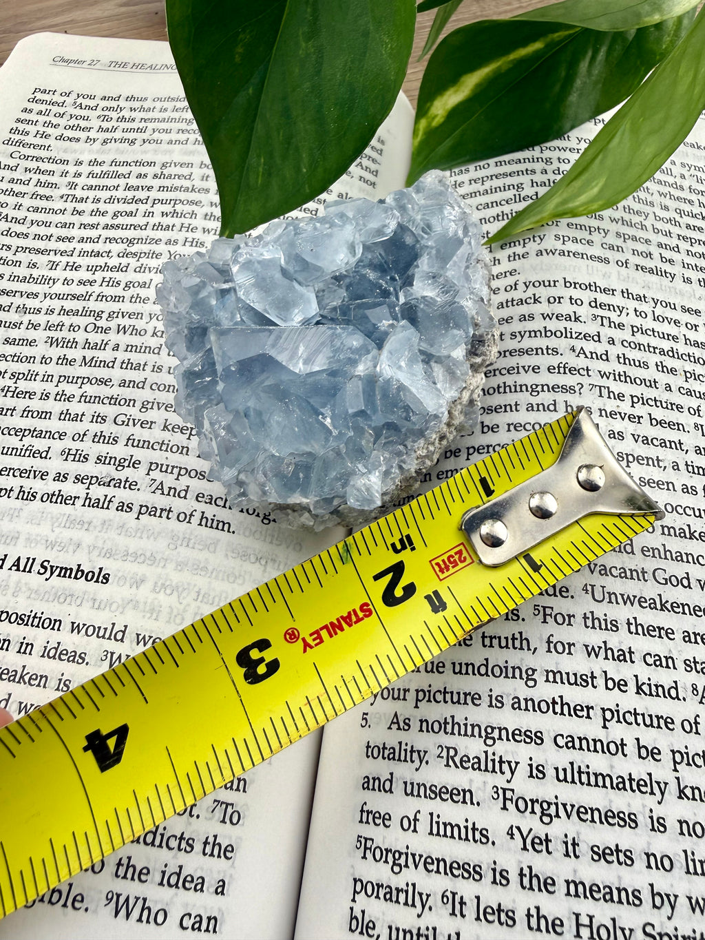 Crystal on an open book with a measuring tape showing it to be approx 2"