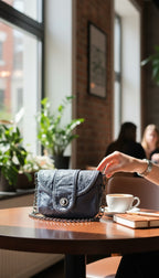 Blue Vegan Leather Mini Chain Crossbody Bag lifestyle photo on table with hand and coffee