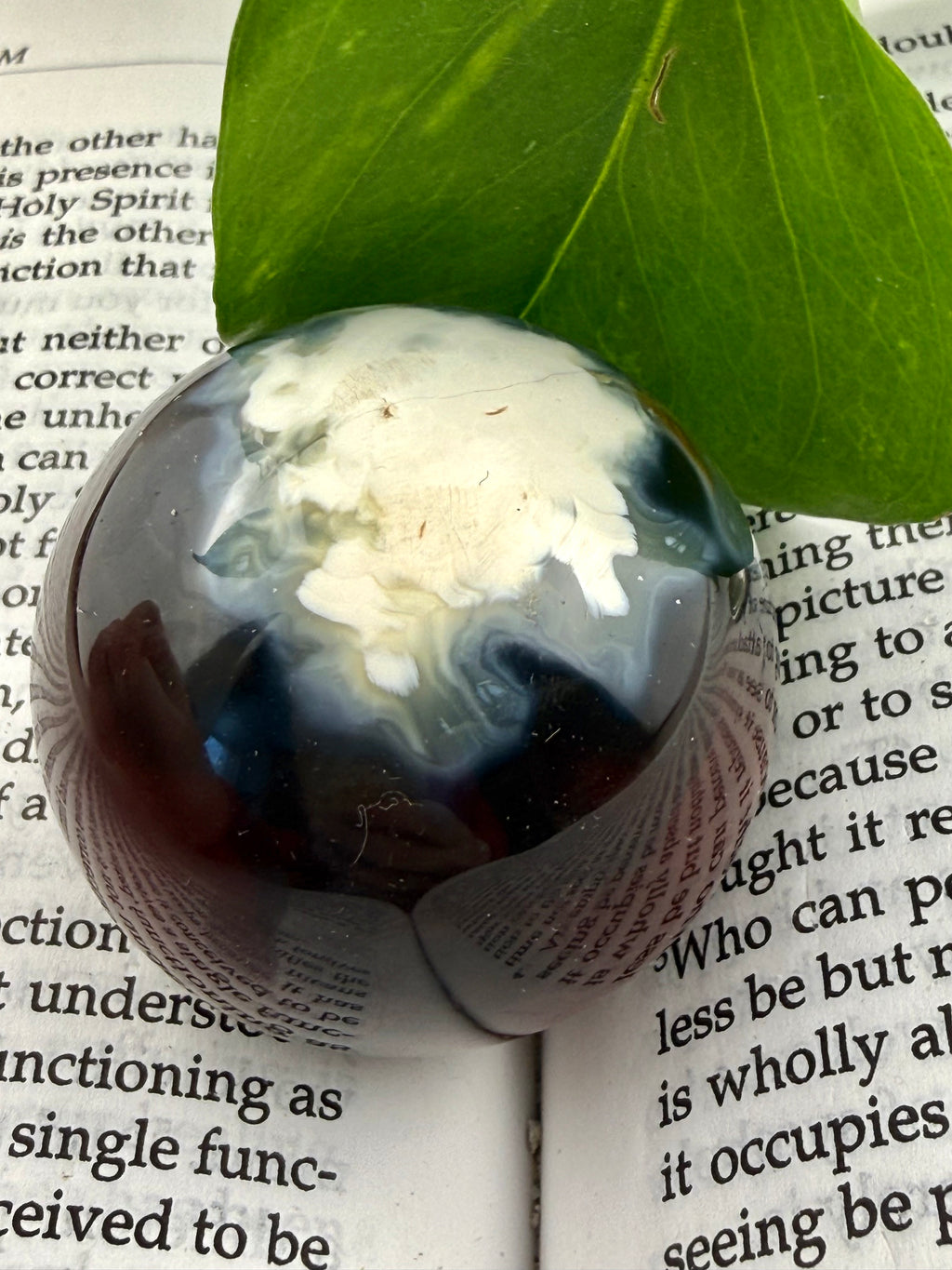 up close of dark carnelian sphere with white pattern on one size 