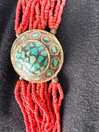 Close up turquoise mosaic inlay medallion on red boho beaded bracelet