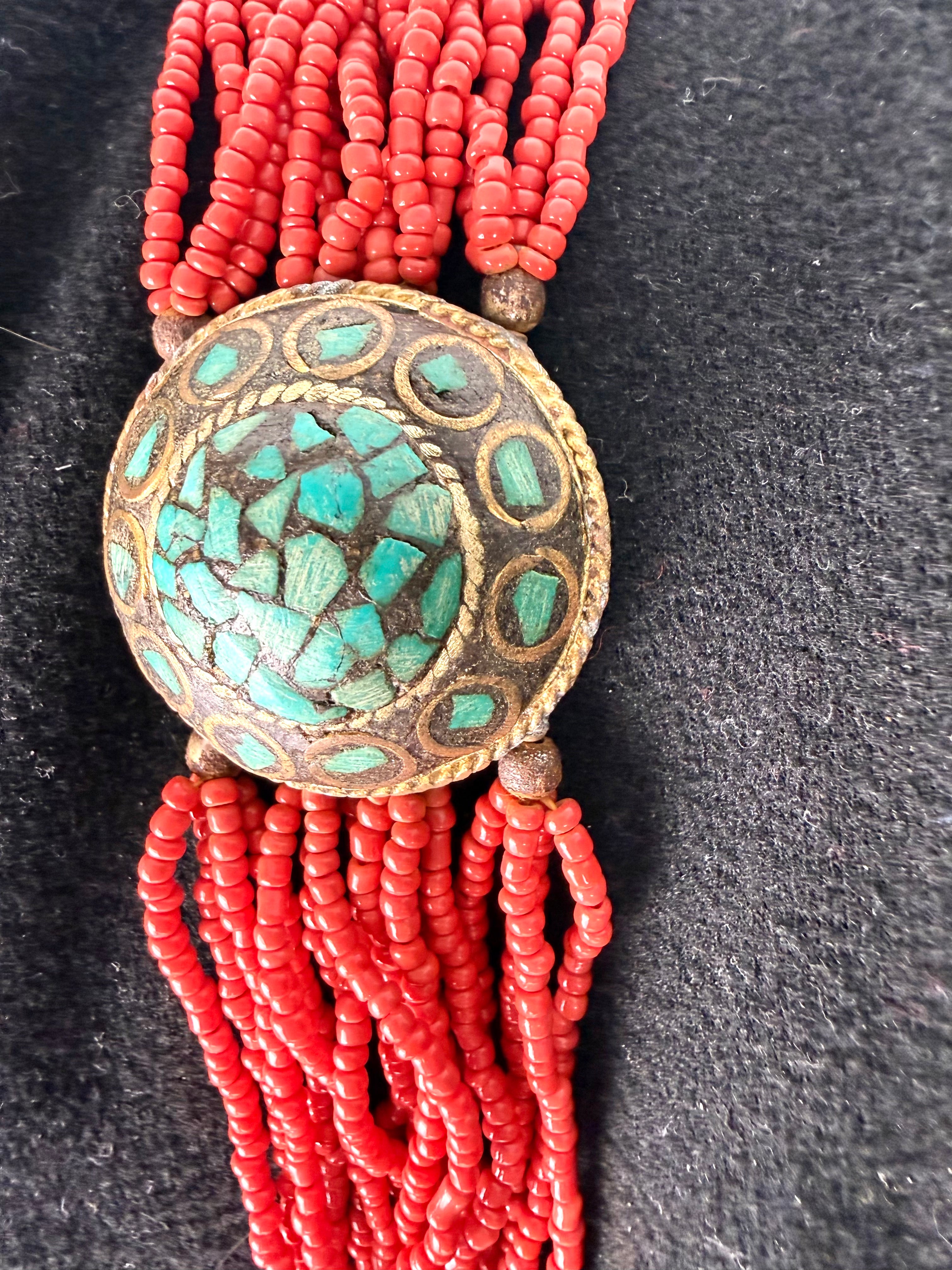 Close up turquoise mosaic inlay medallion on red boho beaded bracelet