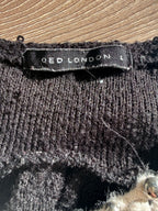 Close-up of Qed London size L label on black knit fabric