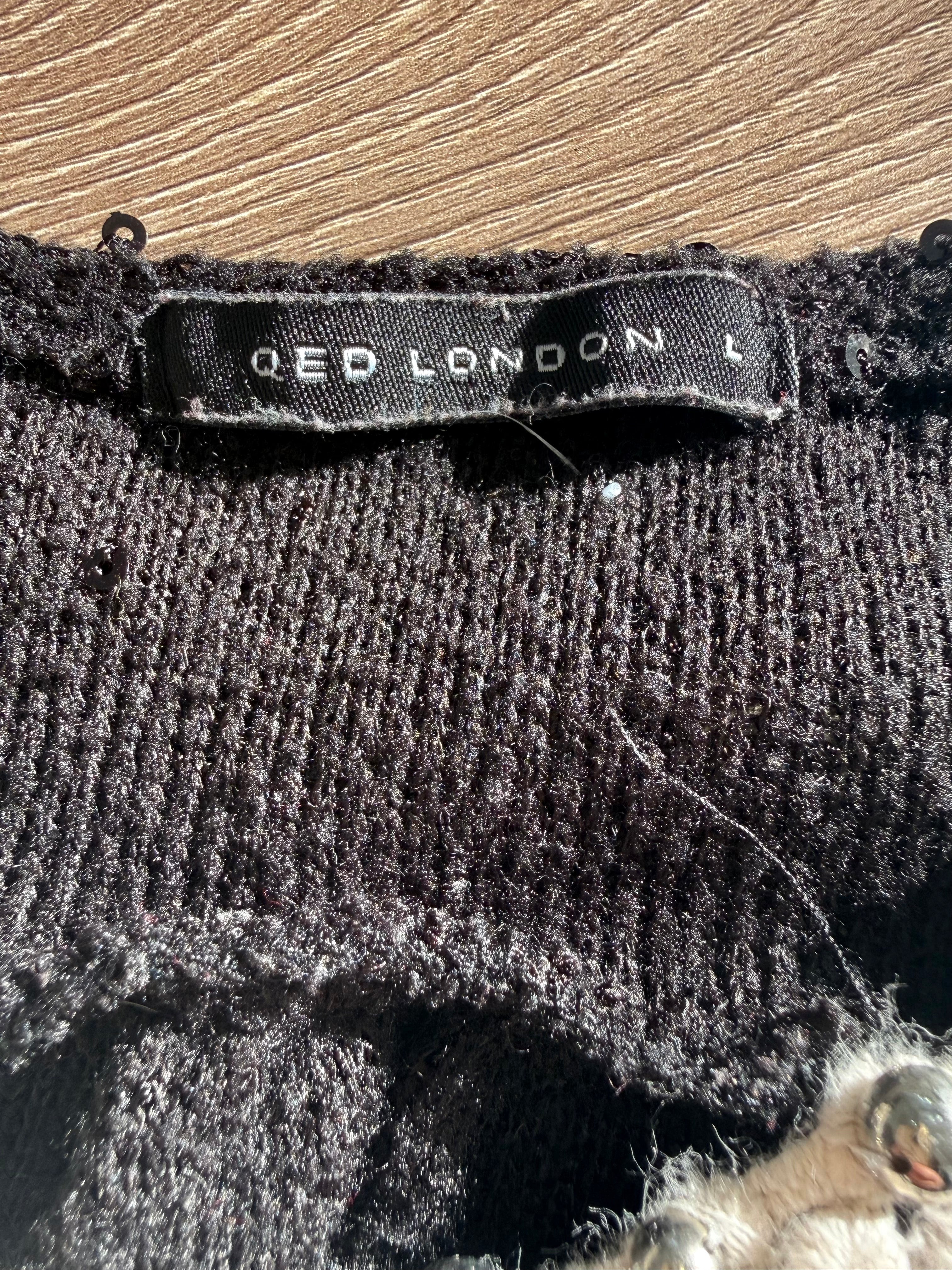 Close-up of Qed London size L label on black knit fabric