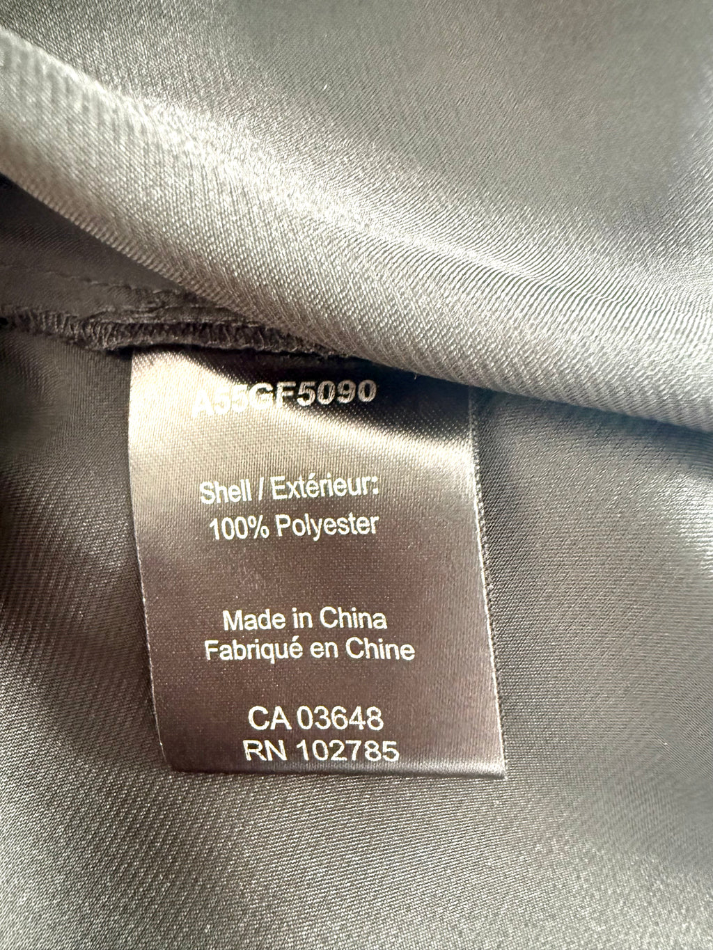 Close-up of fabric content tag showing 100% polyester, made in China.