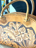 Close-up of hand-tooled floral embossing on vintage tan leather handbag