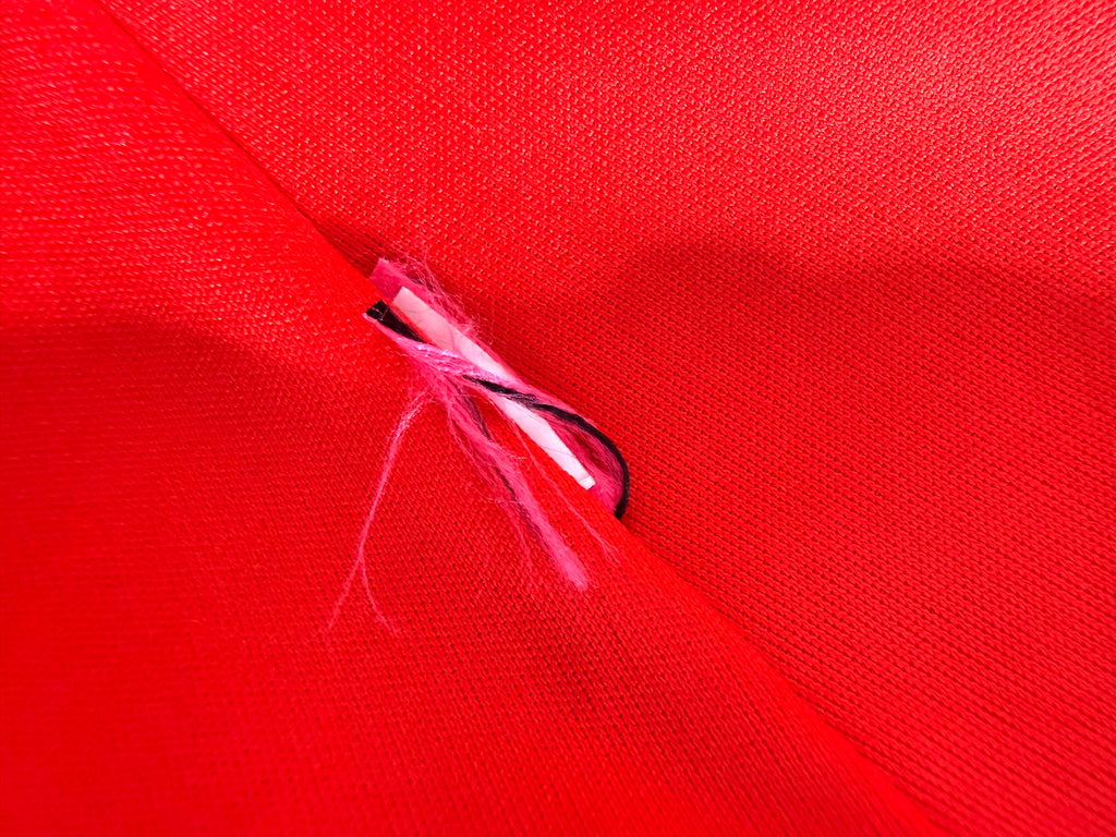 Close-up of red textured fabric and interior seam detail on Betsey Johnson dress.