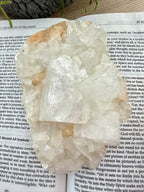 Apophyllite crystal on an open book with a natural background