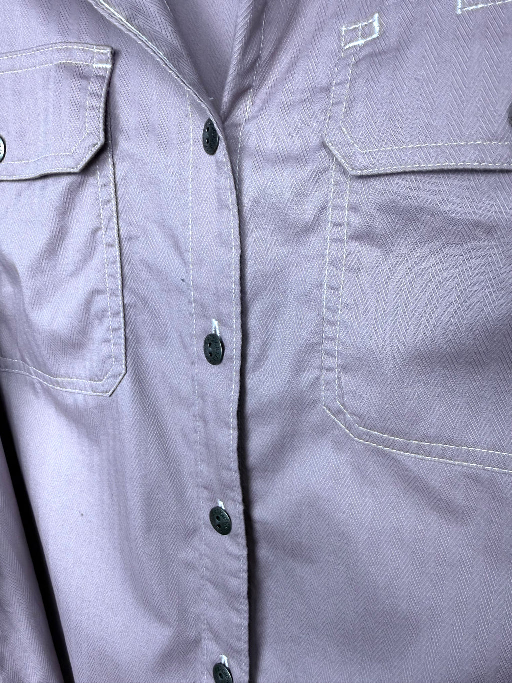 Close up of Dickies branded button and cargo flap chest pocket on dusty rose herringbone work shirt.