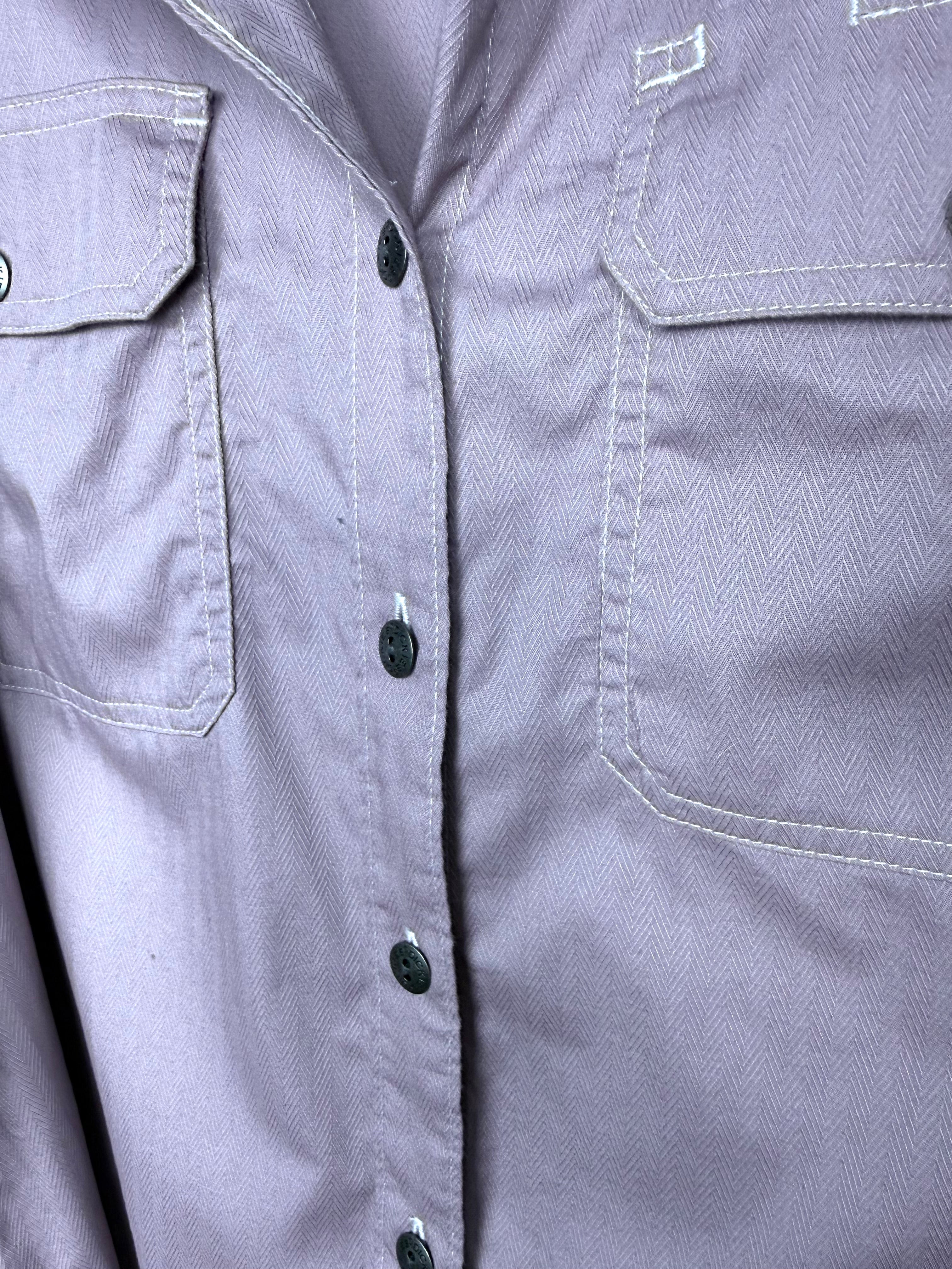 Close up of Dickies branded button and cargo flap chest pocket on dusty rose herringbone work shirt.