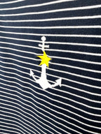 Close up of white anchor and yellow star detail on nautical striped sweater.