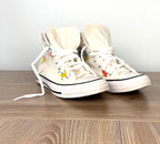 Converse Chuck Taylor floral high top sneakers in cream canvas with colourful flower print, front view.