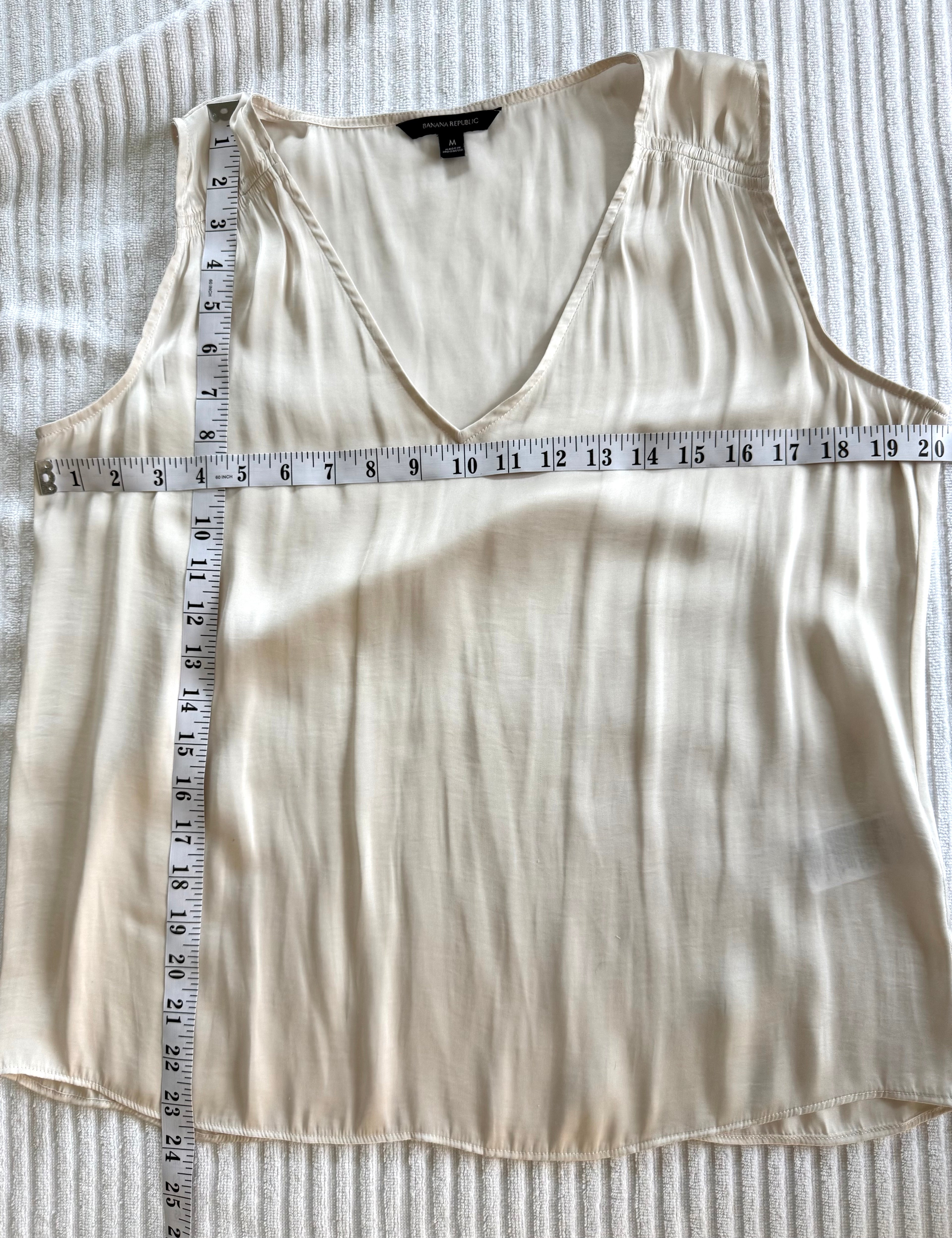 Cream Banana Republic sleeveless blouse featuring a V-neckline, gathered shoulder detail, relaxed silhouette, and fluid drape throughout the body measuring 40" bust and 23" shoulder to hem