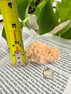 Stilbite crystal on book with measuring tape to show it's 2 inches high 