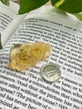 yellow fluorite on an open book with a dime for scale 