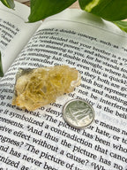 yellow fluorite on an open book with a dime for scale 