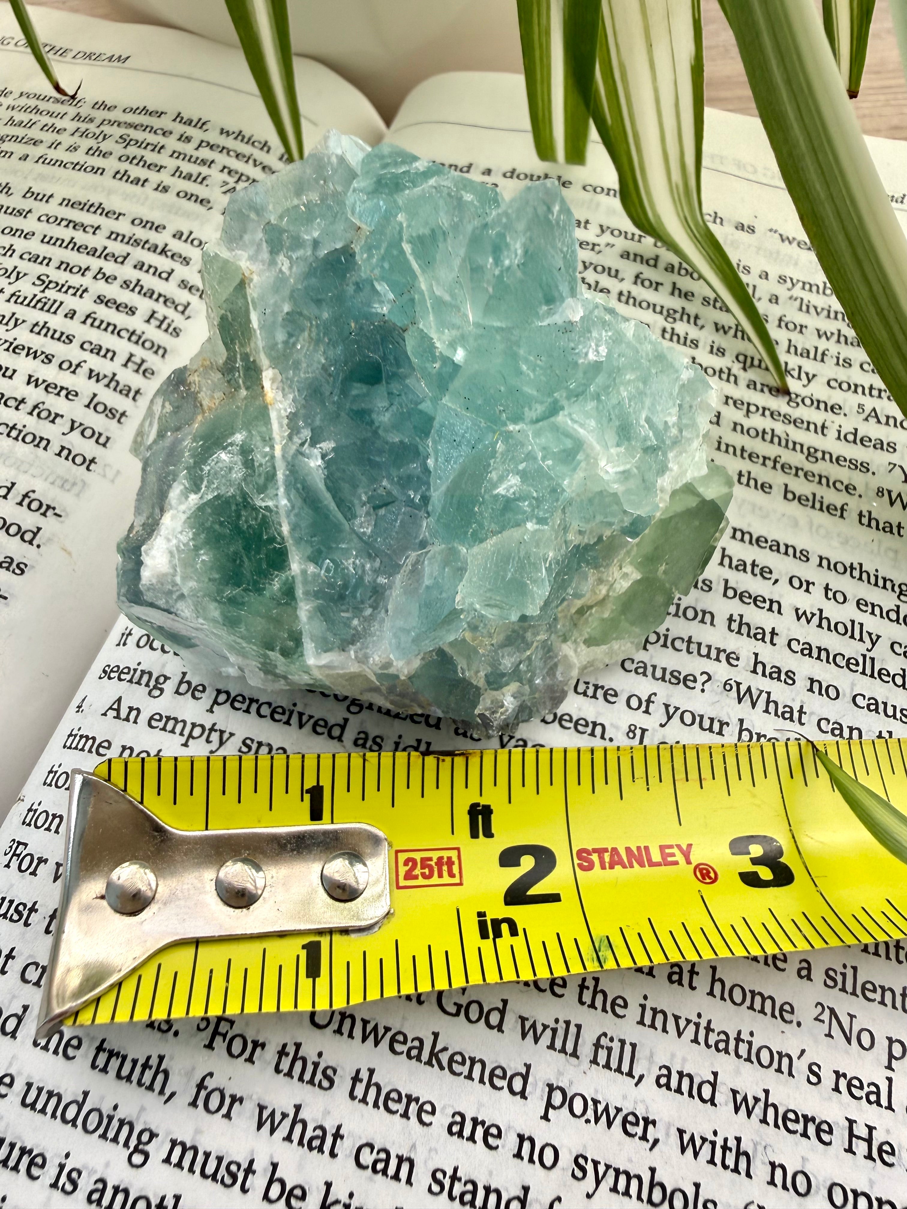 Fluorite  crystal on top of a book with a measuring tape for scale