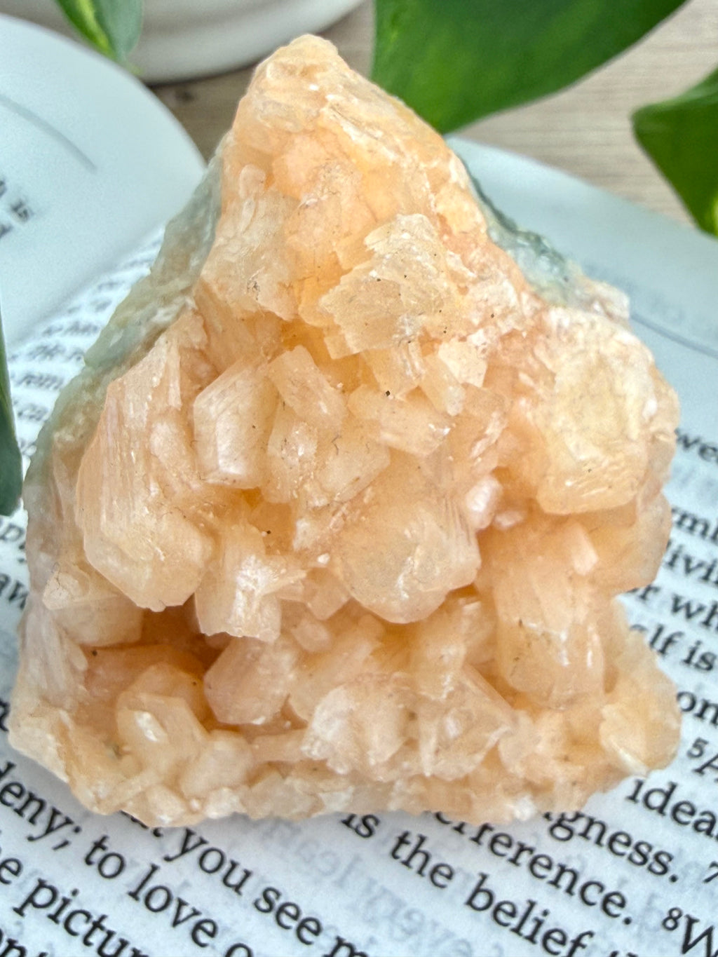Stilbite crystal up close standing on a book 