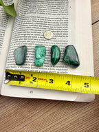 4 pieces of green malachite on an open book with a measuring tape 