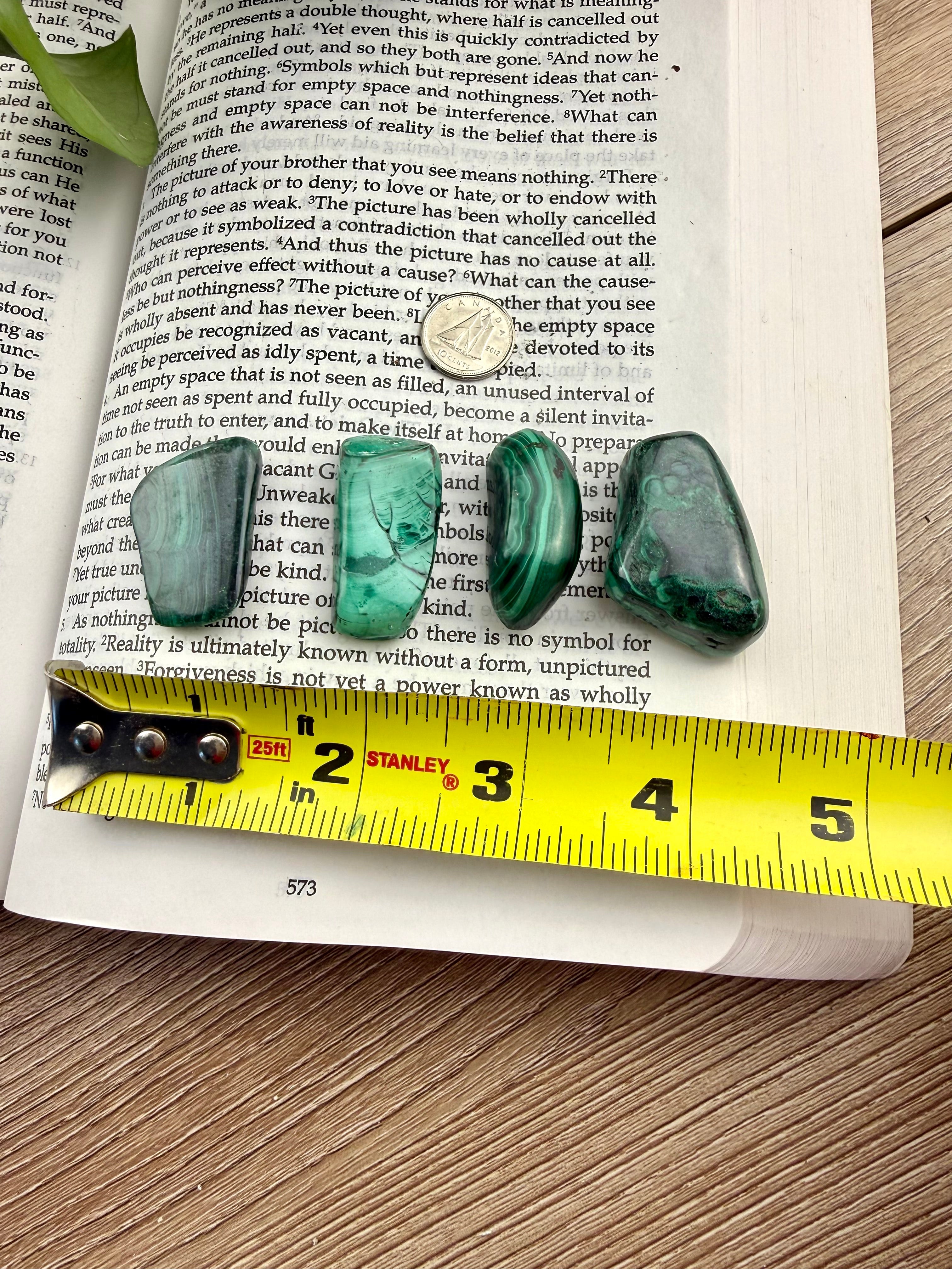 4 pieces of green malachite on an open book with a measuring tape 