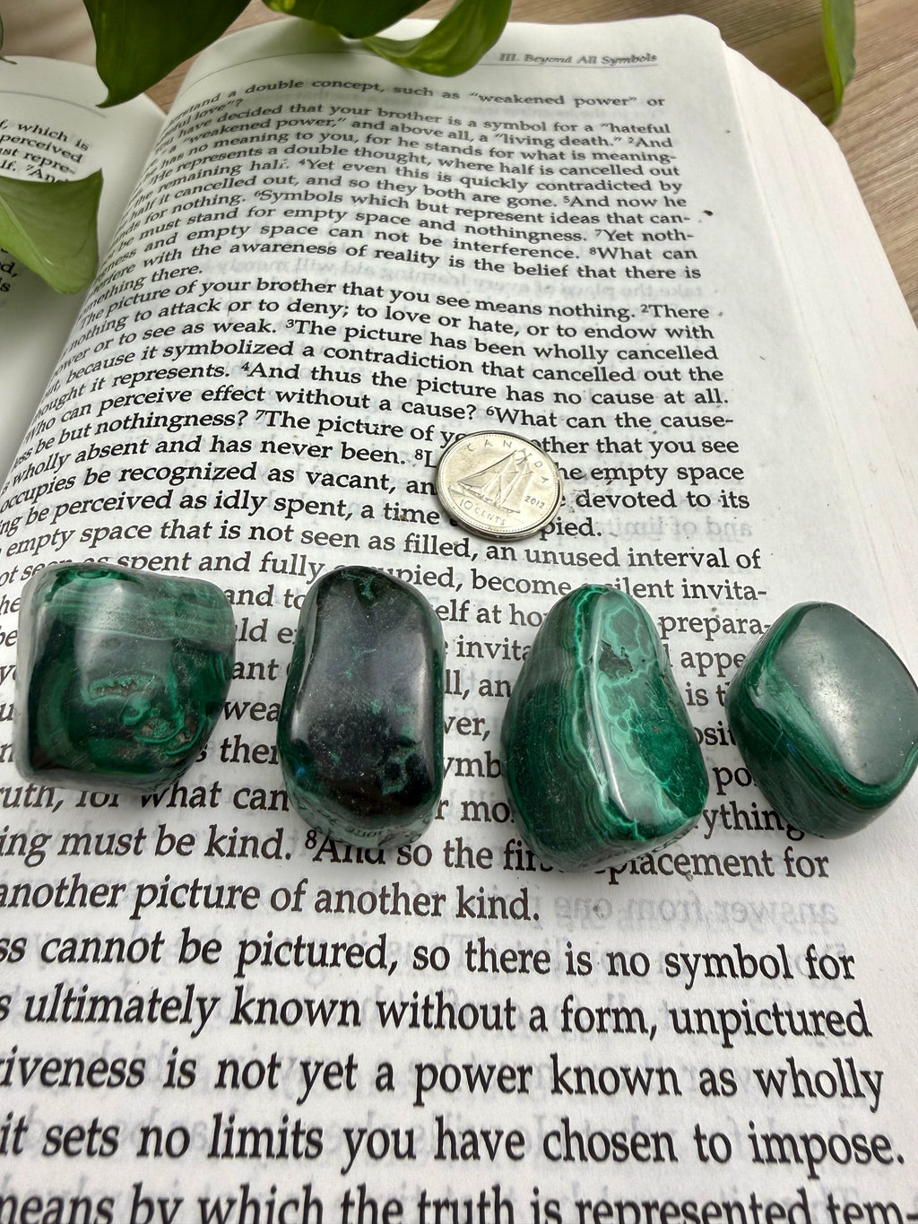 4 Malachite tumbles on a book with a dime for scale