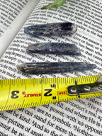 Three dark stone objects on top of an open book with a ruler for scale. These measure from 2-3 inches
