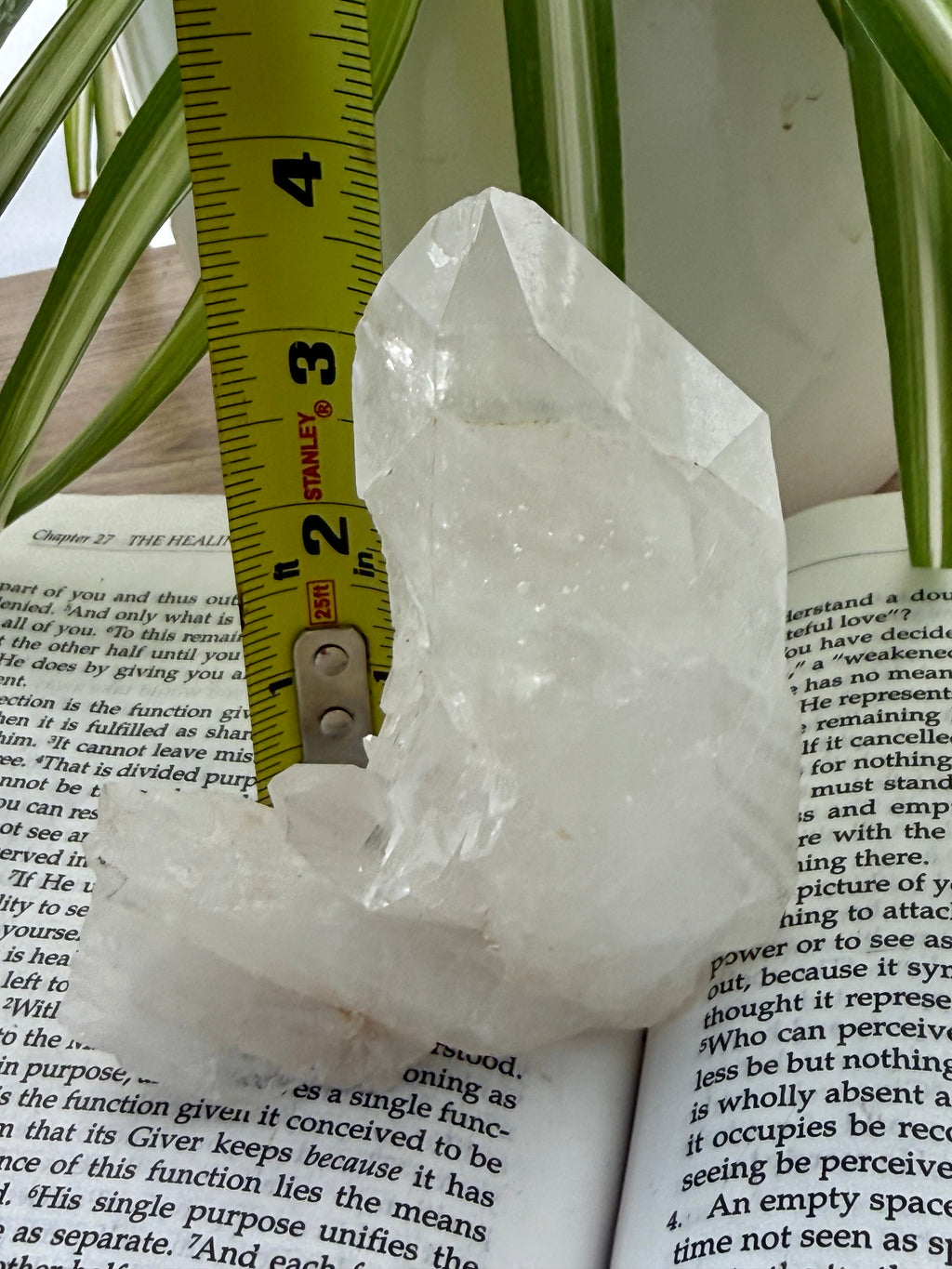 Clear quartz crystal on an open book with a ruler for scale