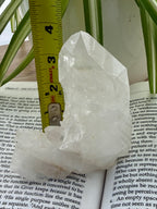 Clear quartz crystal on an open book with a ruler for scale