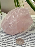 rose quartz on a book with a dime to show scale 
