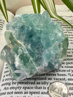 Green fluorite crystal rock on a book with a coin for scale