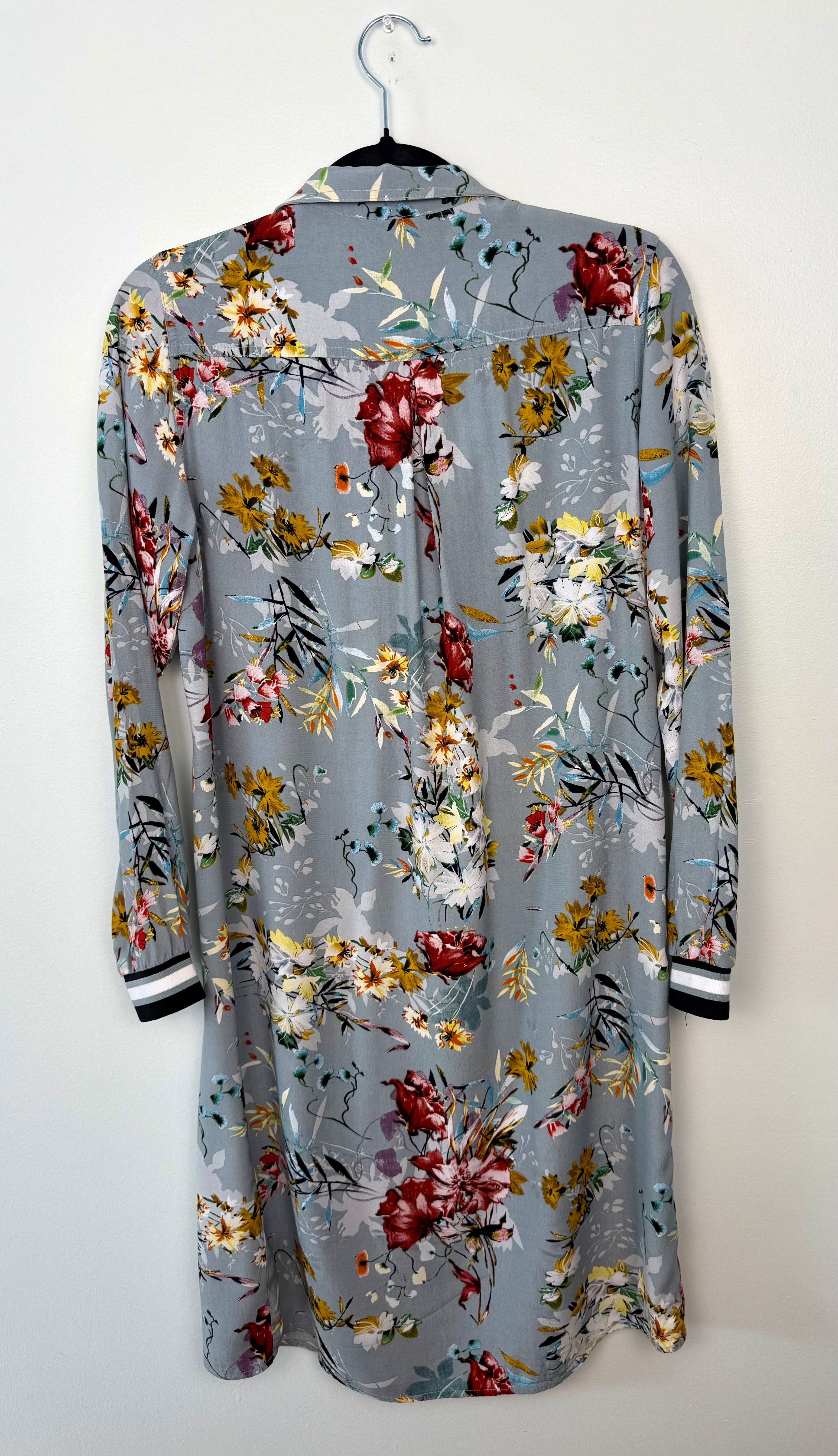 back of floral-patterned shirt on a hanger against a white background