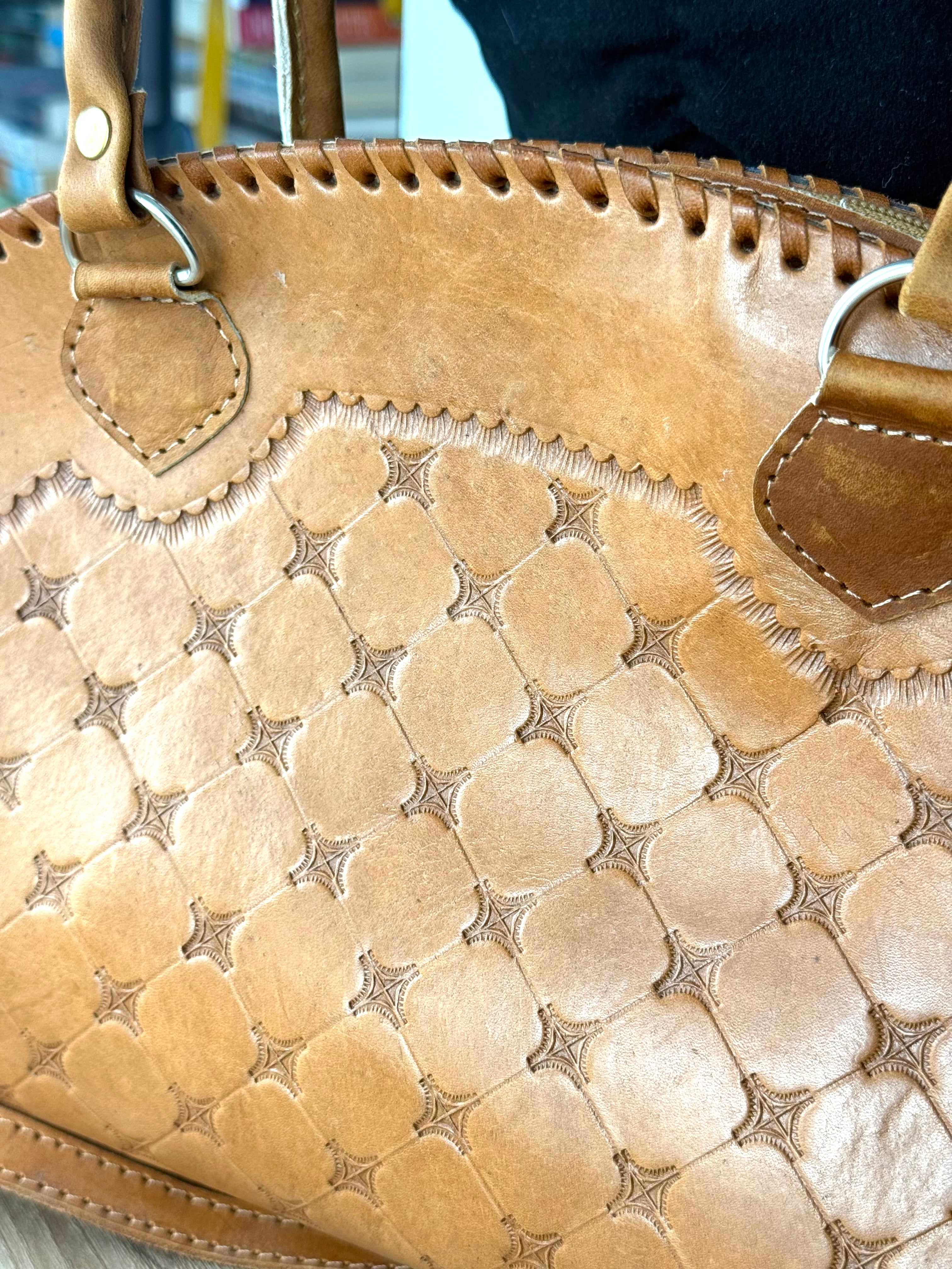 Detailed view of geometric tooled leather pattern on back of vintage handbag
