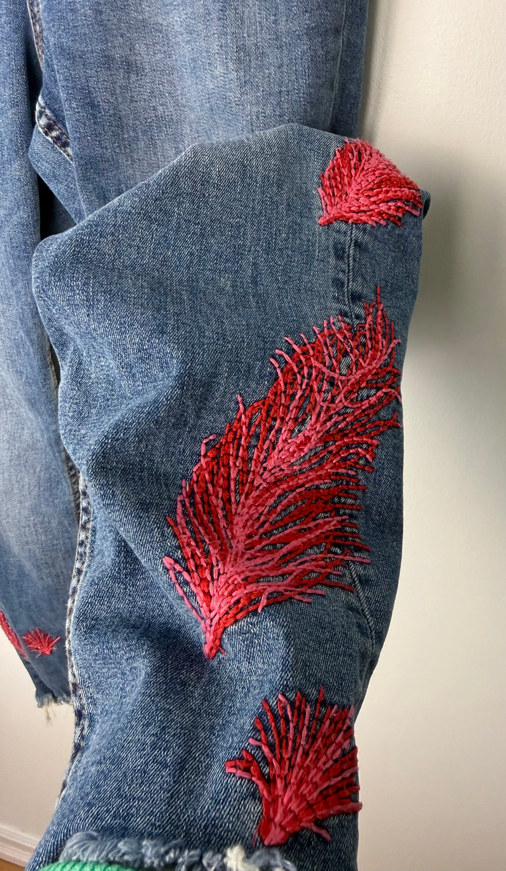 Dex embroidered feather skinny jeans medium wash distressed raw hem at Blue Sparrow Shop  close up of embroidery on left leg