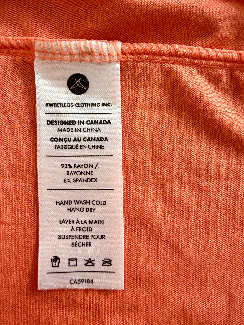 Fabric tag on an orange garment with text and symbols.
