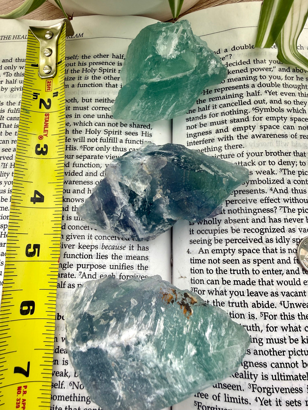 Three fluorite crystals on a book with a measuring tape for scale.